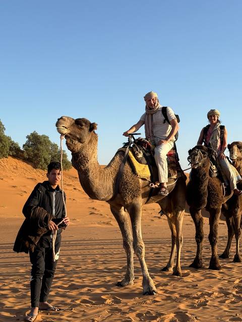       People riding camels in the desert.
  