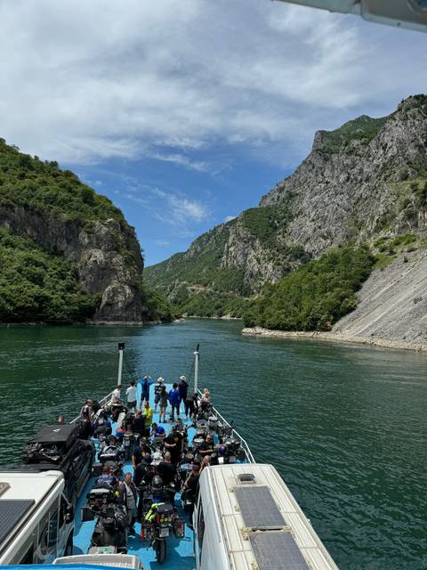 A crowded boat navigating a river through a canyon.