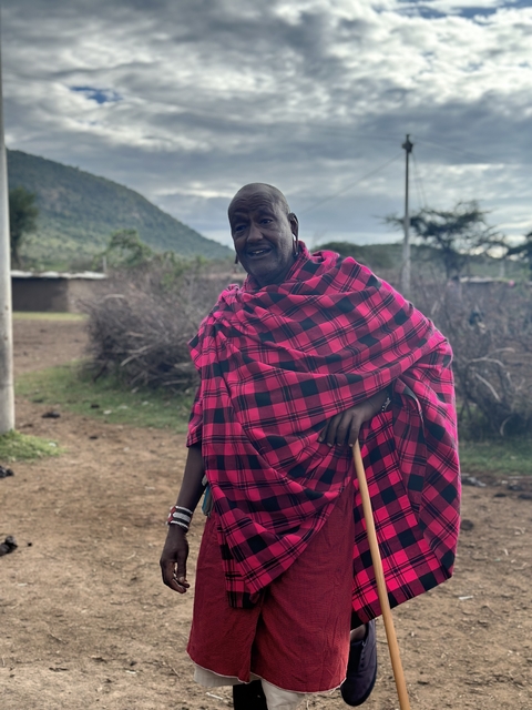 Person in traditional Maasai attire with landscape background.