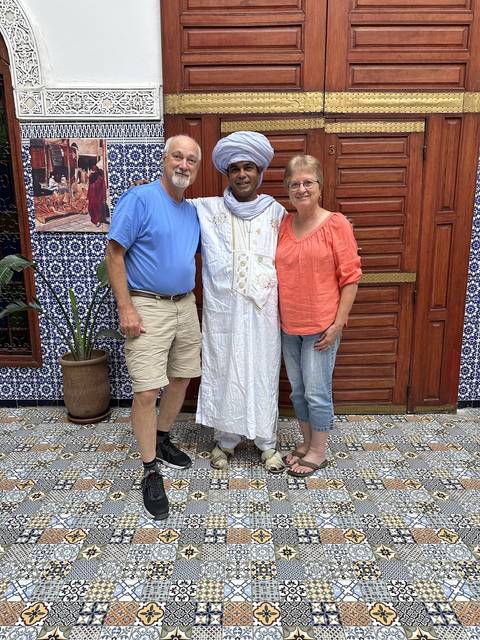 Three people posing in front of a wooden door with traditional tiles.