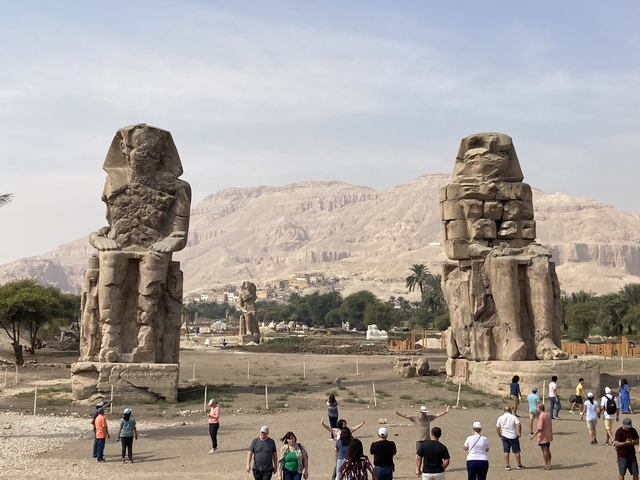       Colossal statues set against a mountainous backdrop.
  
