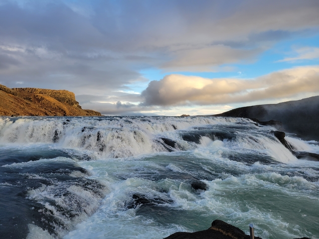 Wide waterfall with flowing water and cloudy sky.