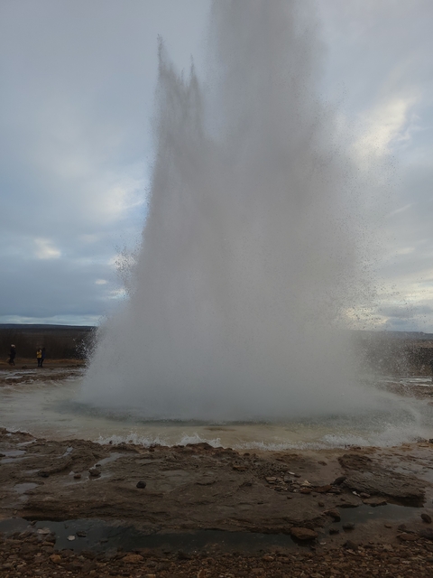 Water geyser erupting with people watching.