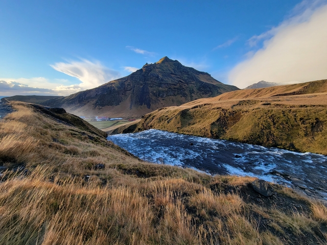 Mountain landscape with grass and a waterfall.