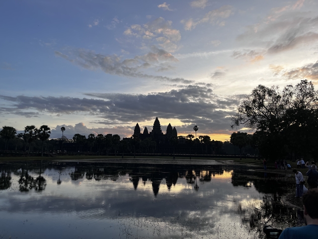 Silhouette of a temple at sunrise over water.
