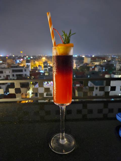      Cocktail with a straw and garnish on a counter overlooking a city.
  