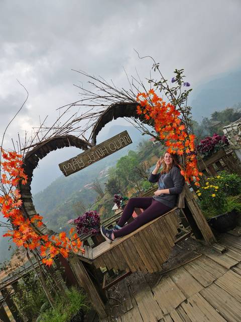       Person sitting on a wooden structure decorated with flowers and a sign.
  