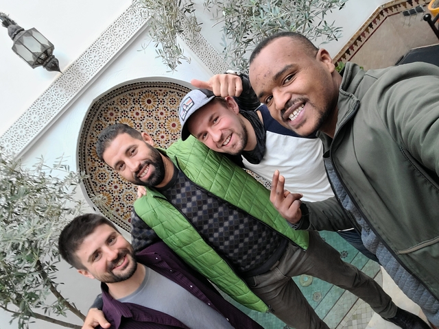 Four friends posing in front of a traditional Moroccan mosaic.