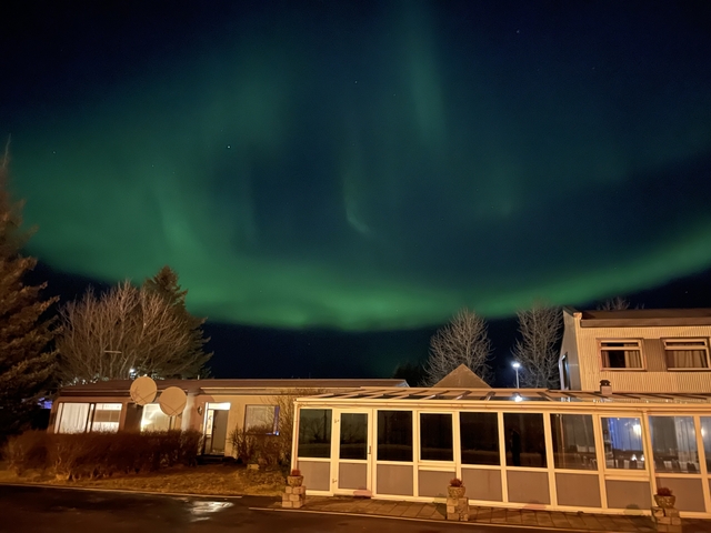       Northern lights over buildings at night.
  