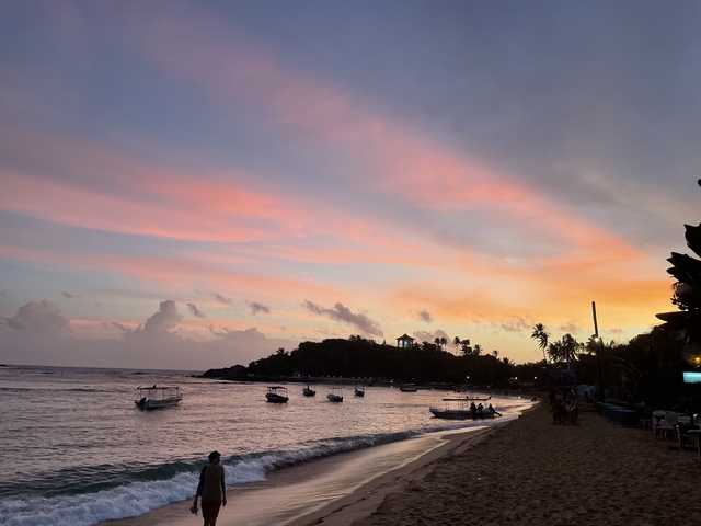 Colorful sunset over a beach with boats.