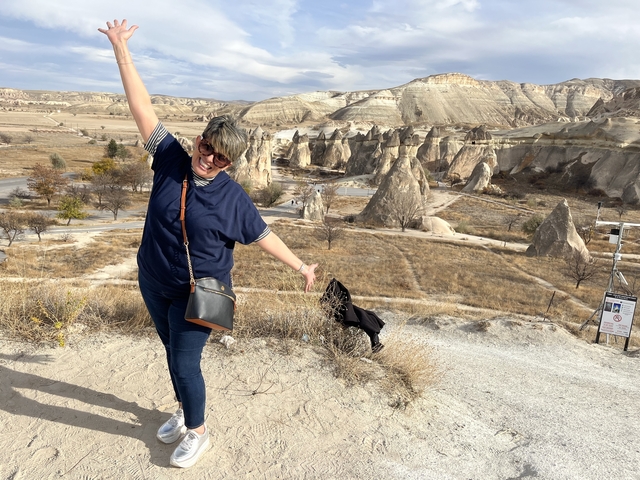 Tourist posing with dramatic landscape in background.