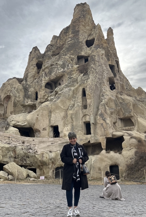 Person standing in front of a rock formation with caves.