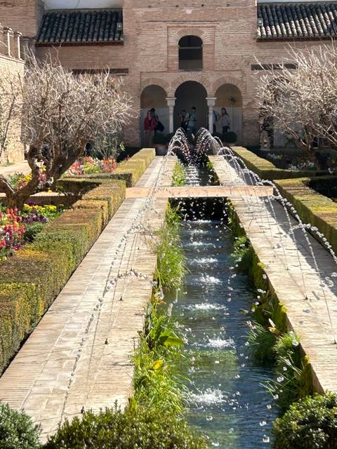 Reflective pool with arches and greenery.