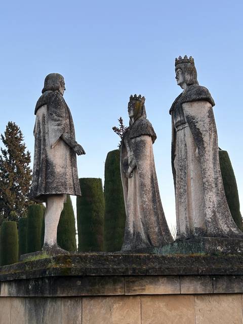 Statues in a garden setting with trees.