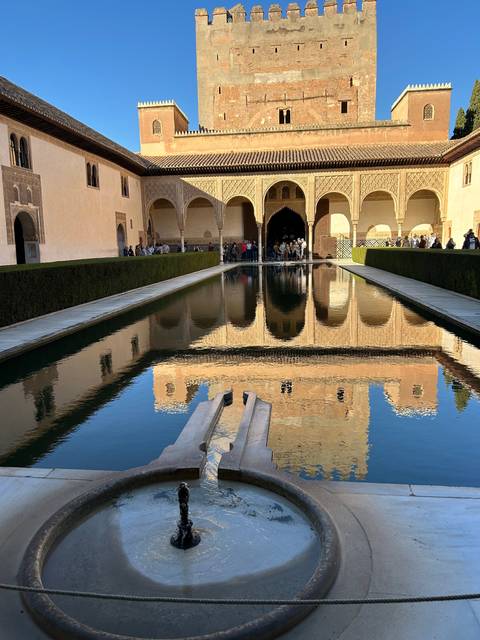       Large historic building reflected in a pool.
  