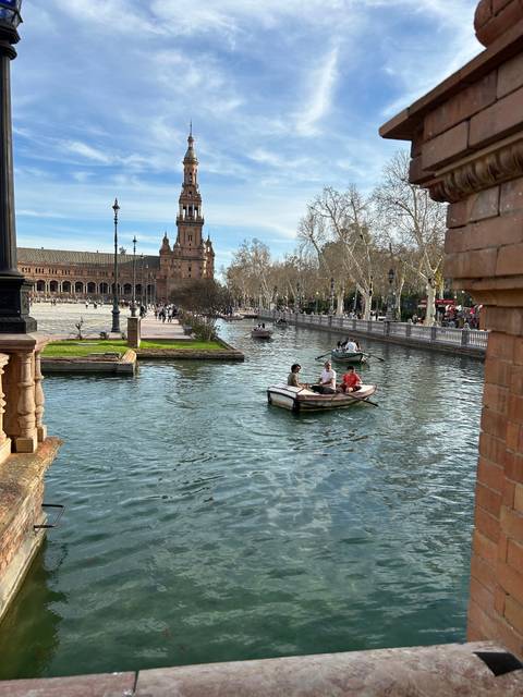 People boating in a canal with historical buildings.