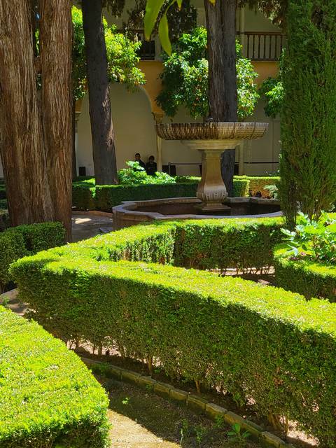 Lush garden with trimmed hedges and a fountain.