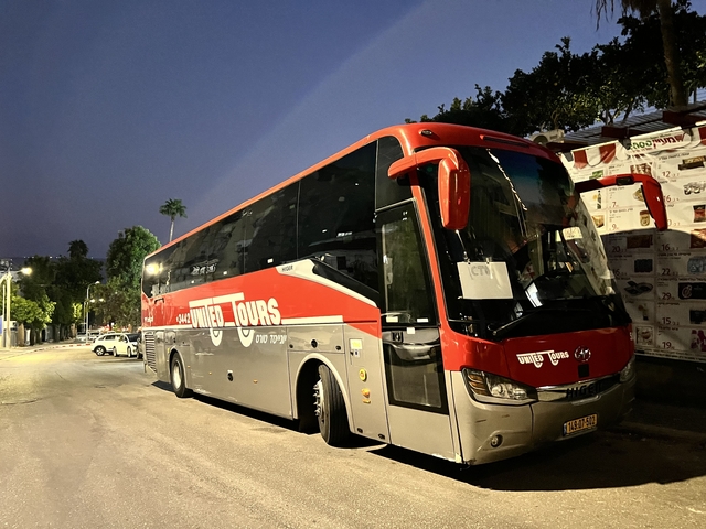       Tour bus parked on the street at dusk.
  