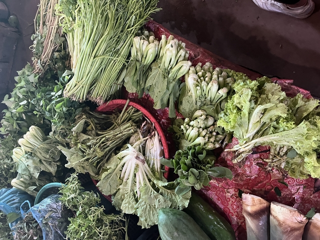       Variety of fresh leafy vegetables in a market setting.
  