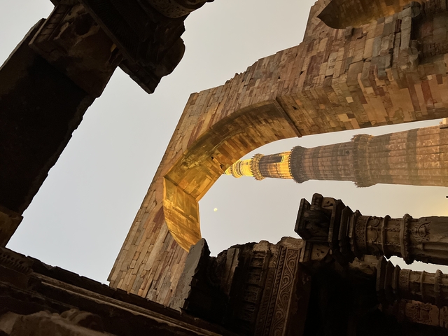 A historical tower viewed through an archway, illuminated at dusk.