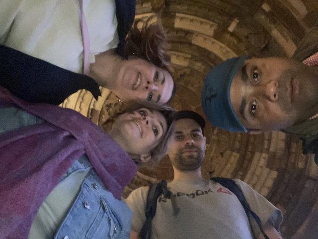 Four people posing inside a historical structure.