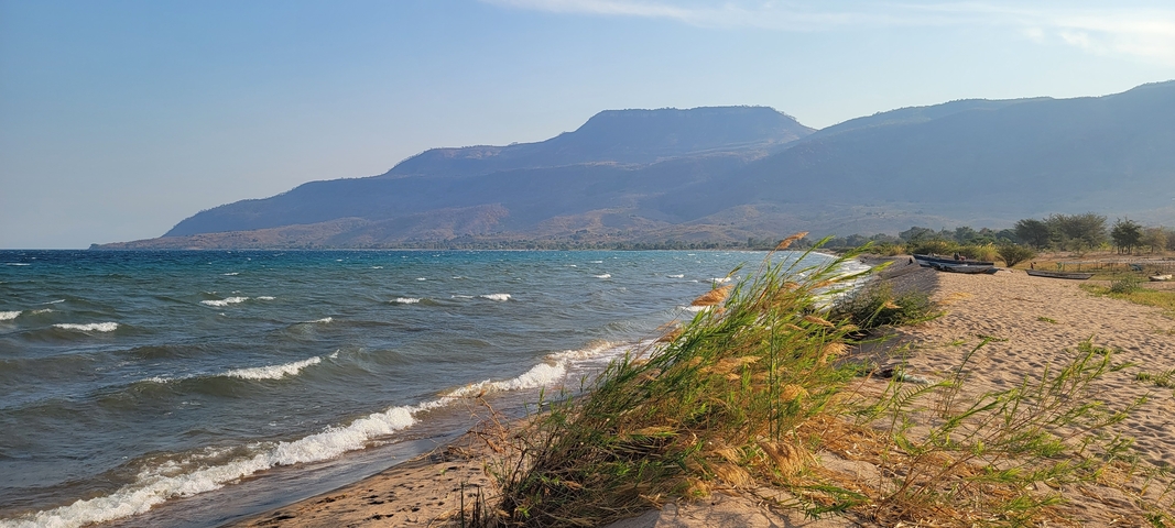 Beach with waves and mountain backdrop.