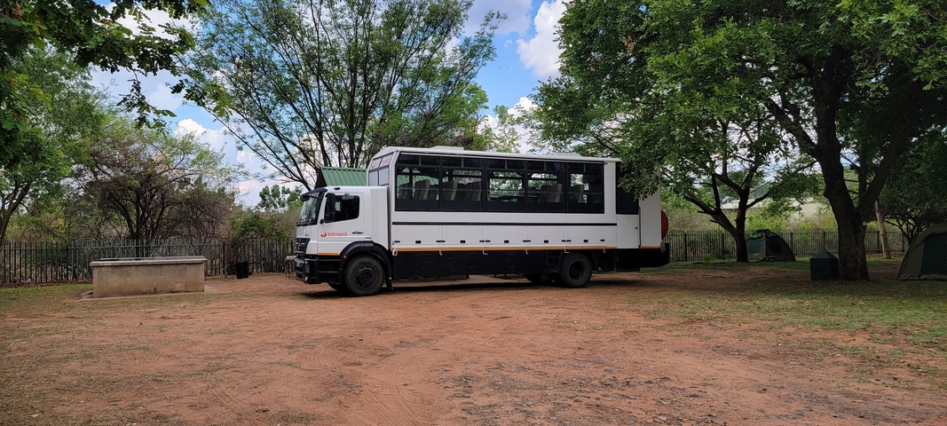 A large truck parked in a campsite with trees.