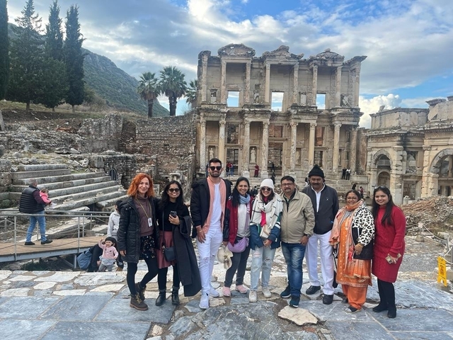 Group of tourists posing in front of ancient ruins.
