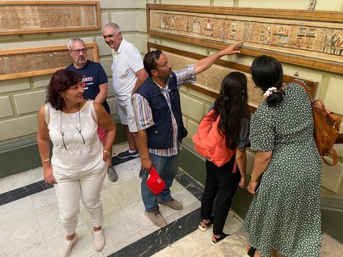 Tour guide explaining wall carvings to a group of tourists.
