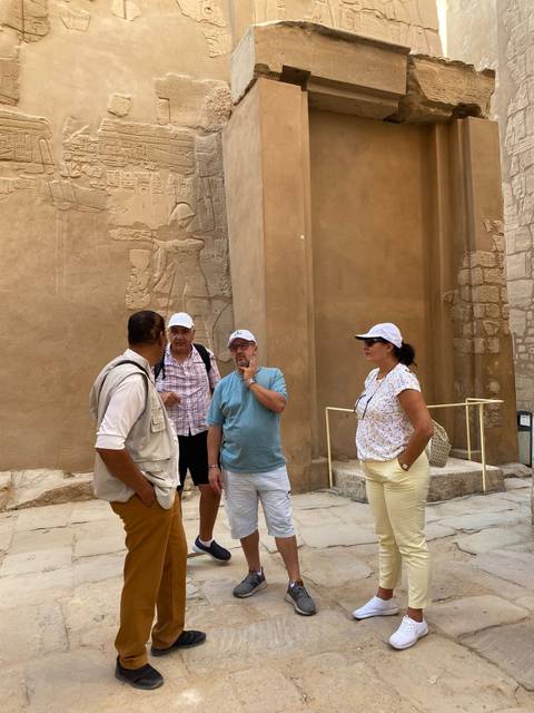 Tourists listening to a guide near an ancient structure.