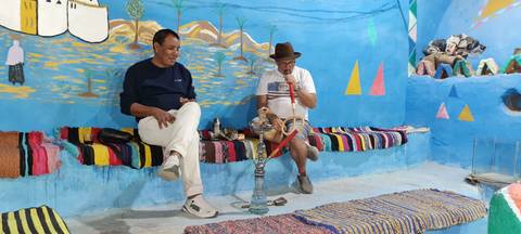       People relaxing and smoking shisha in a colorful indoor setting.
  