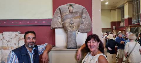      Two tourists posing with an ancient stone sculpture.
  