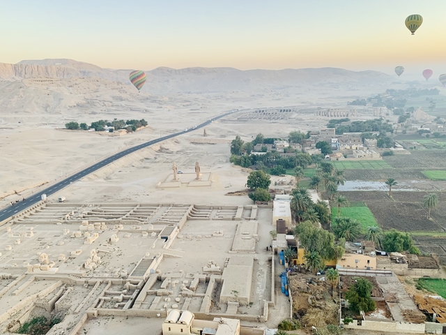       Aerial view of a desert landscape with hot air balloons.
  