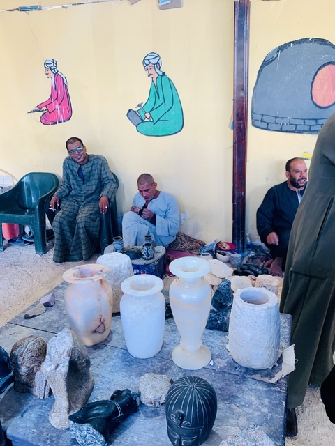       Group of men sitting indoors with stone items.
  