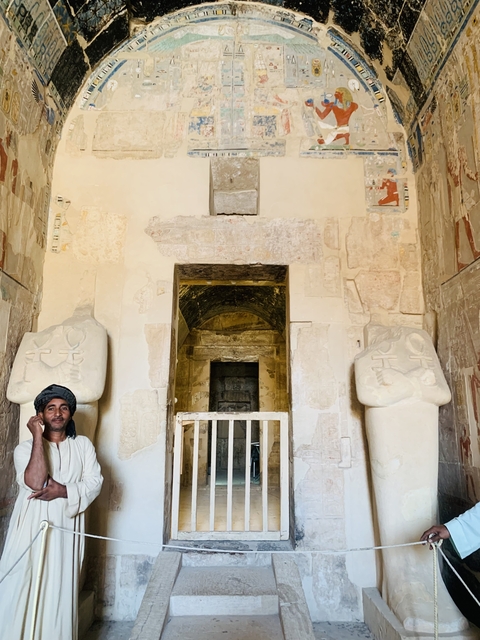 Person seated next to ancient carvings.