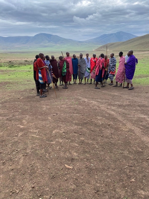 A group of people dressed in traditional colorful garments standing on a clearing.