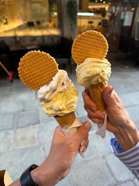       Close-up of hands holding gelato with waffle cones.
  