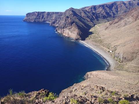 Cliffs and a secluded beach adjacent to a deep blue ocean.