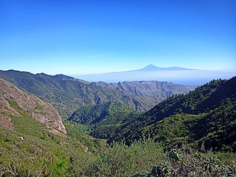       Scenic view of mountains and valleys with a distant peak.
  