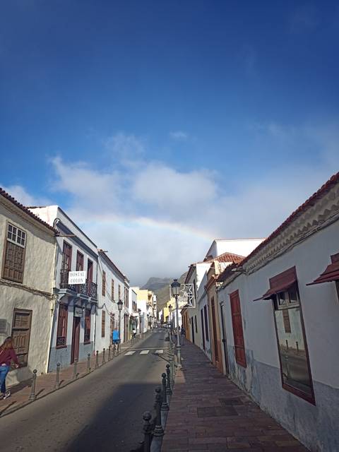 Street view with traditional buildings and a rainbow overhead.