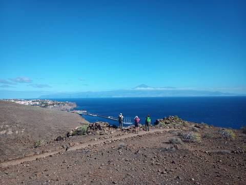      People hiking on a trail with a sea vista in the background.
  