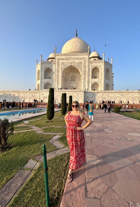 Woman happily posing in front of the majestic Taj Mahal.