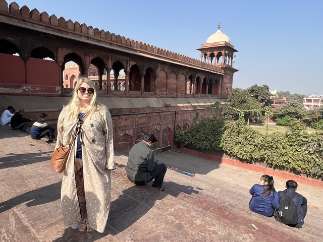 Person posing on steps with a historic fort in the background.