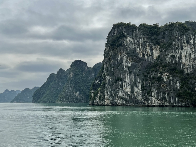       View of limestone karsts over calm green waters.
  
