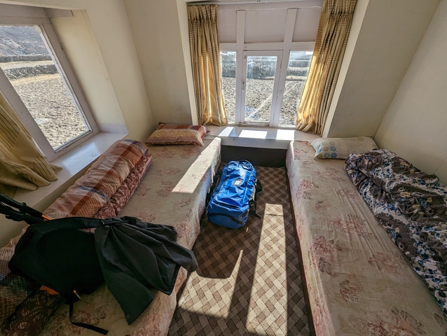 Simple accommodation room with two beds and a backpack.