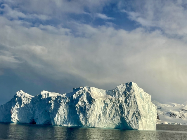Massive iceberg with a dramatic cloudy sky.