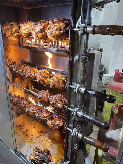 Rotisserie chicken cooking with flames visible.