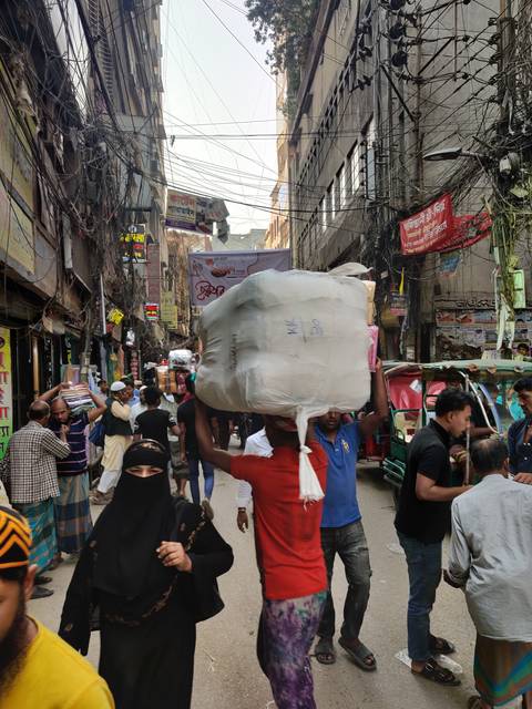       Busy street market with people and power lines overhead.
  