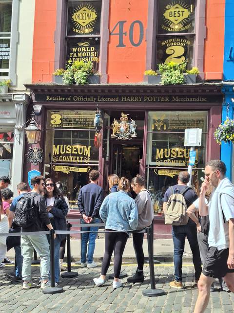       People standing outside a Harry Potter themed store.
  