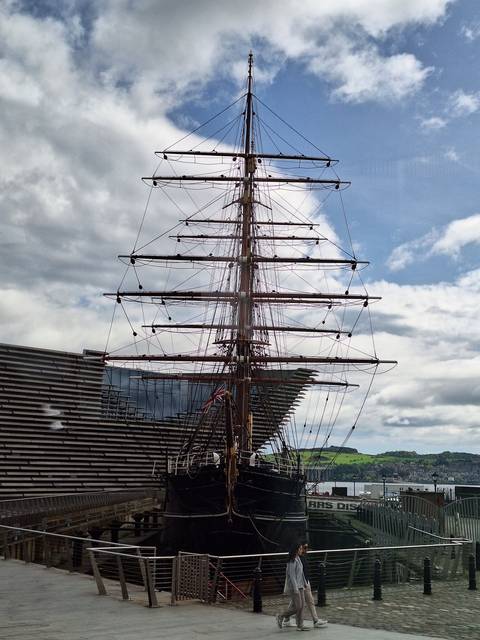 Historic ship docked with a person standing by.
